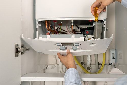 Heating technician repairing a residential boiler in San Fernando