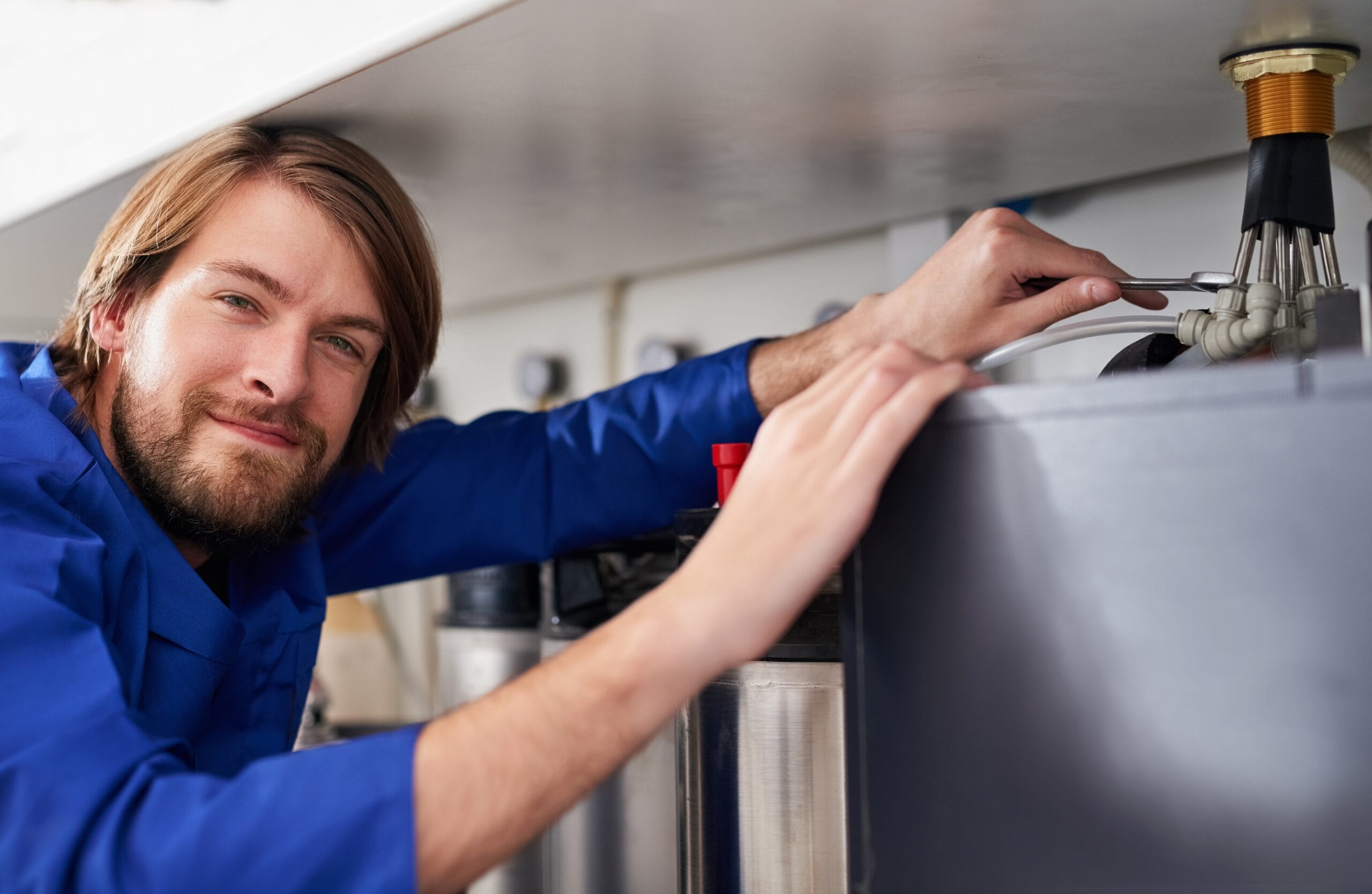Technician servicing a residential water heater tank in San Fernando